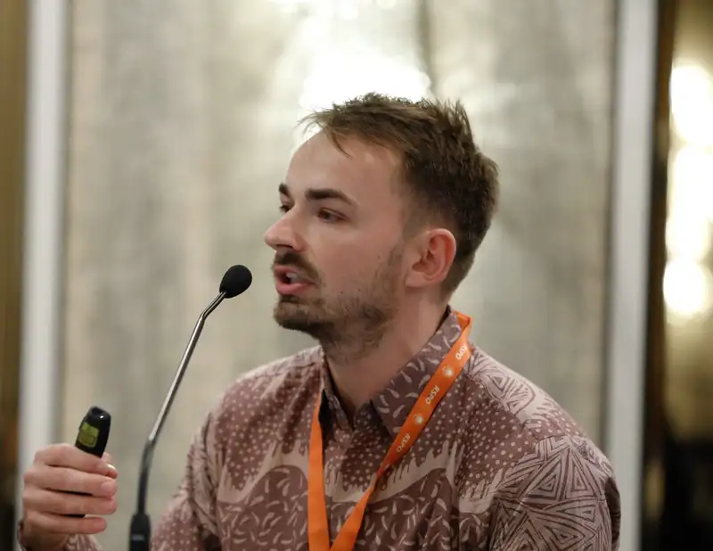 Luca Fischer speaking into a microphone on a conference panel